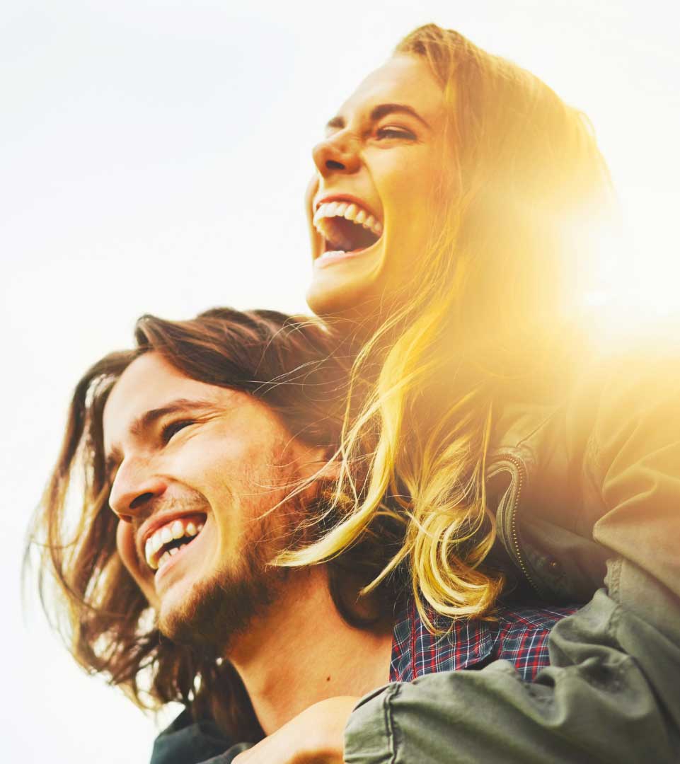 Smiling man carrying his partner on his back while they enjoy time together outside