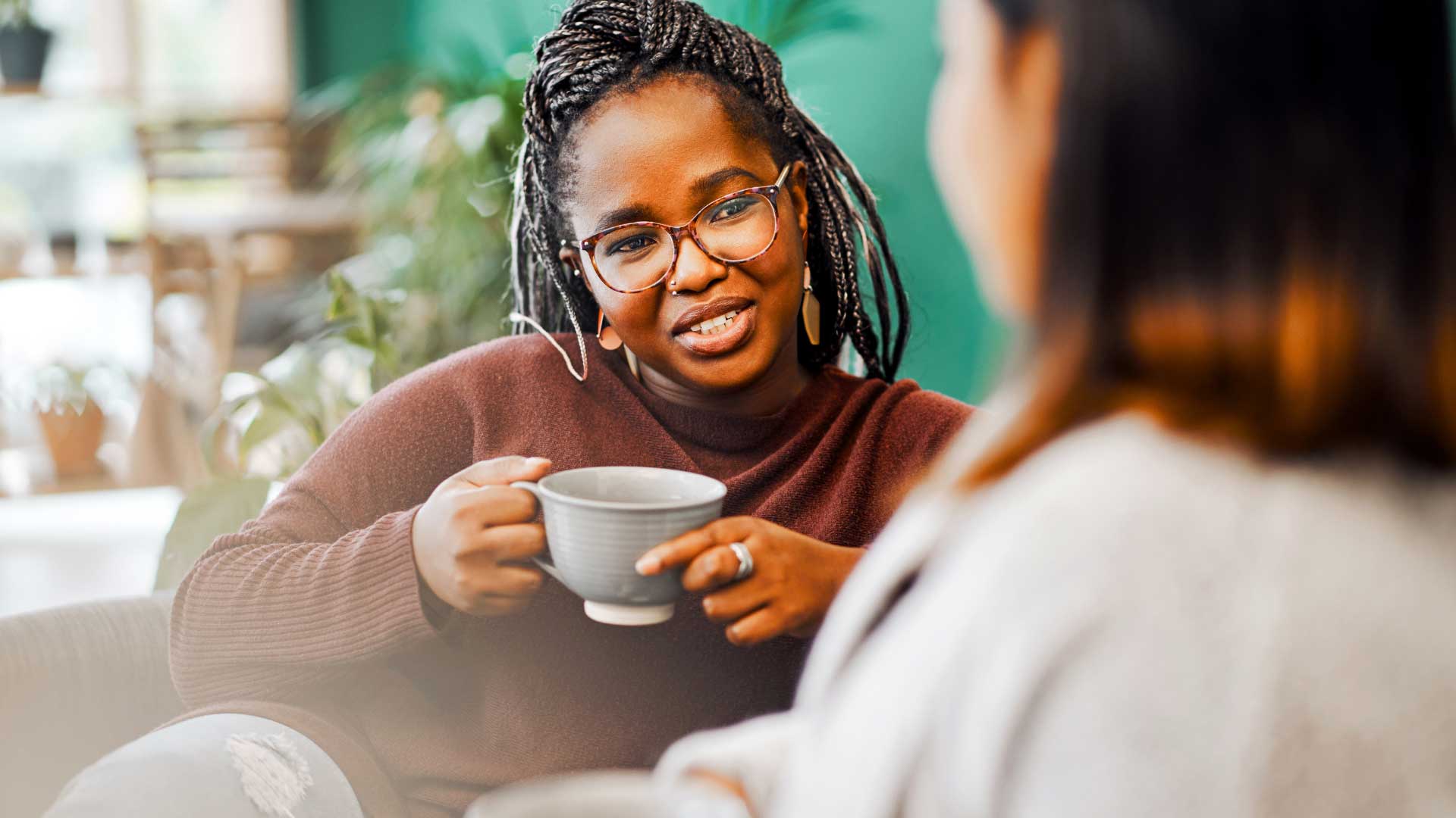 A woman sitting on a couch engaged in conversation with her therapist in a calm, professional setting.