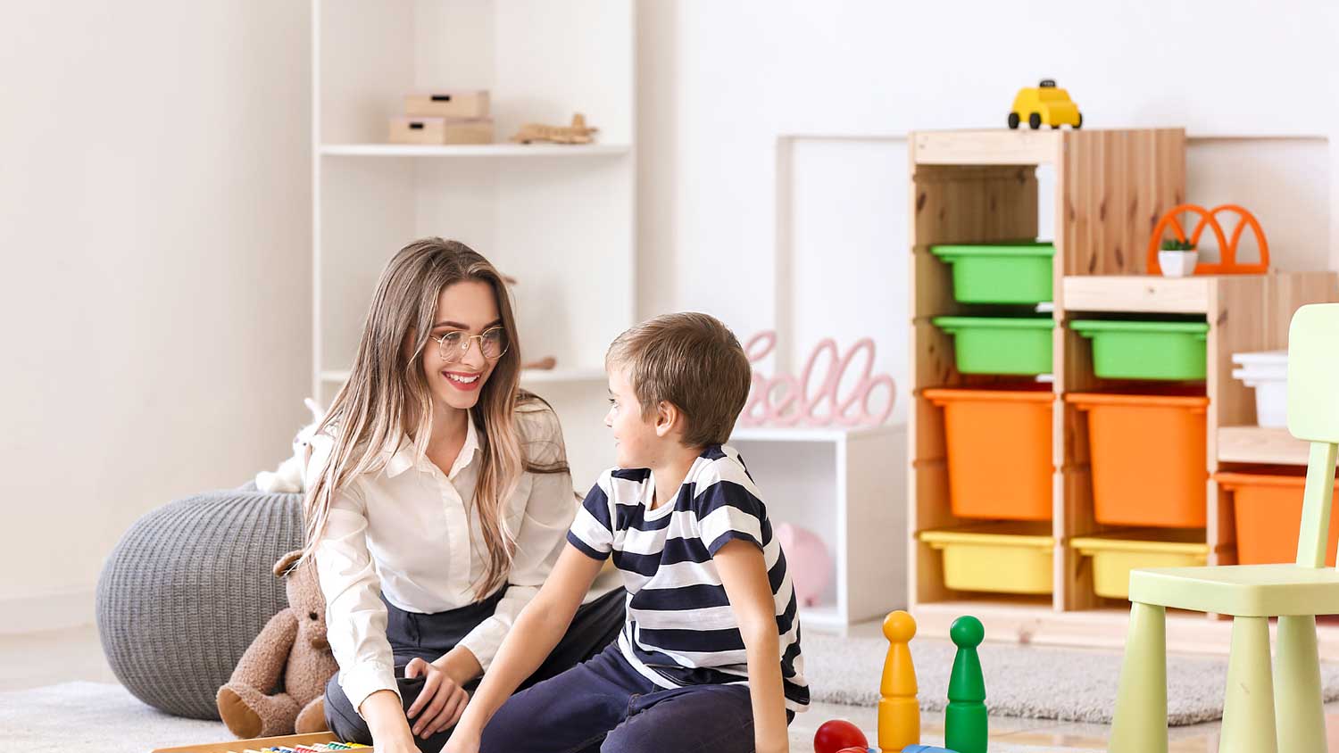 A child and therapist interacting in a colorful therapy room.